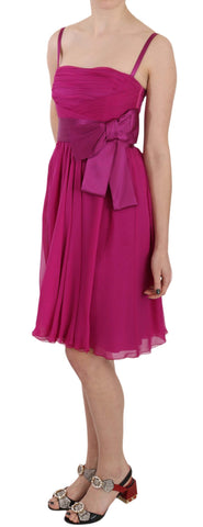 Fuchsia pink bow silk sleeveless dress by Dolce & Gabbana hanging on a clothing rack.