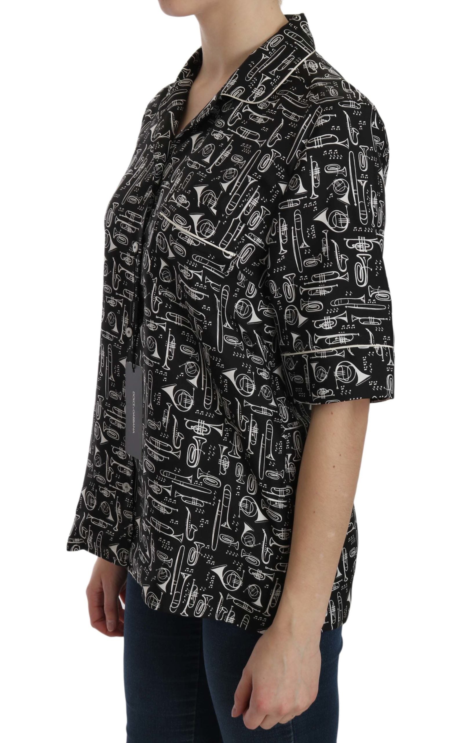 Black Dolce & Gabbana musical instrument print silk top displayed on a hanger with detailed pattern visible.
