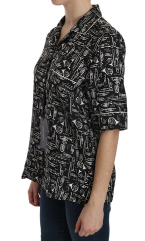 Black Dolce & Gabbana musical instrument print silk top displayed on a hanger with detailed pattern visible.