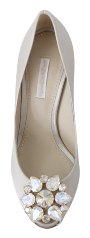 White satin peep toe heels by Dolce & Gabbana featuring crystal embellishments and elegant pump design.