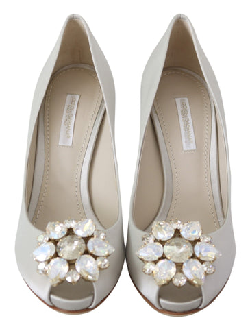 White satin Dolce & Gabbana peep toe heels with crystal embellishments and elegant design.