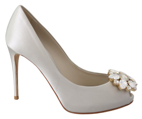 White satin peep toe heels from Dolce & Gabbana featuring crystal embellishments and elegant pump design.