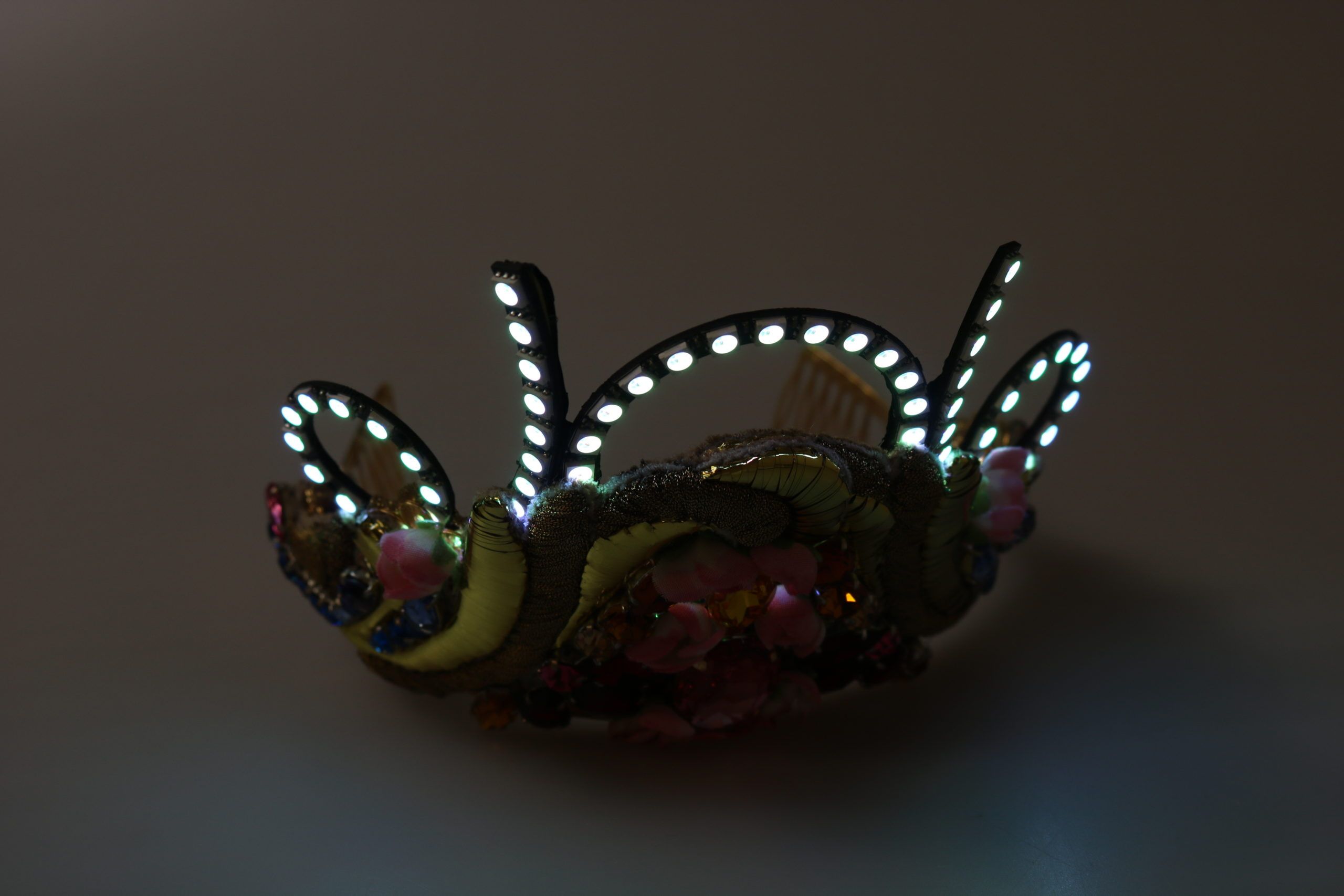 Gold brass floral crown with crystals, LED lights, tiara, and diadem design by Dolce & Gabbana, featuring intricate floral detailing.
