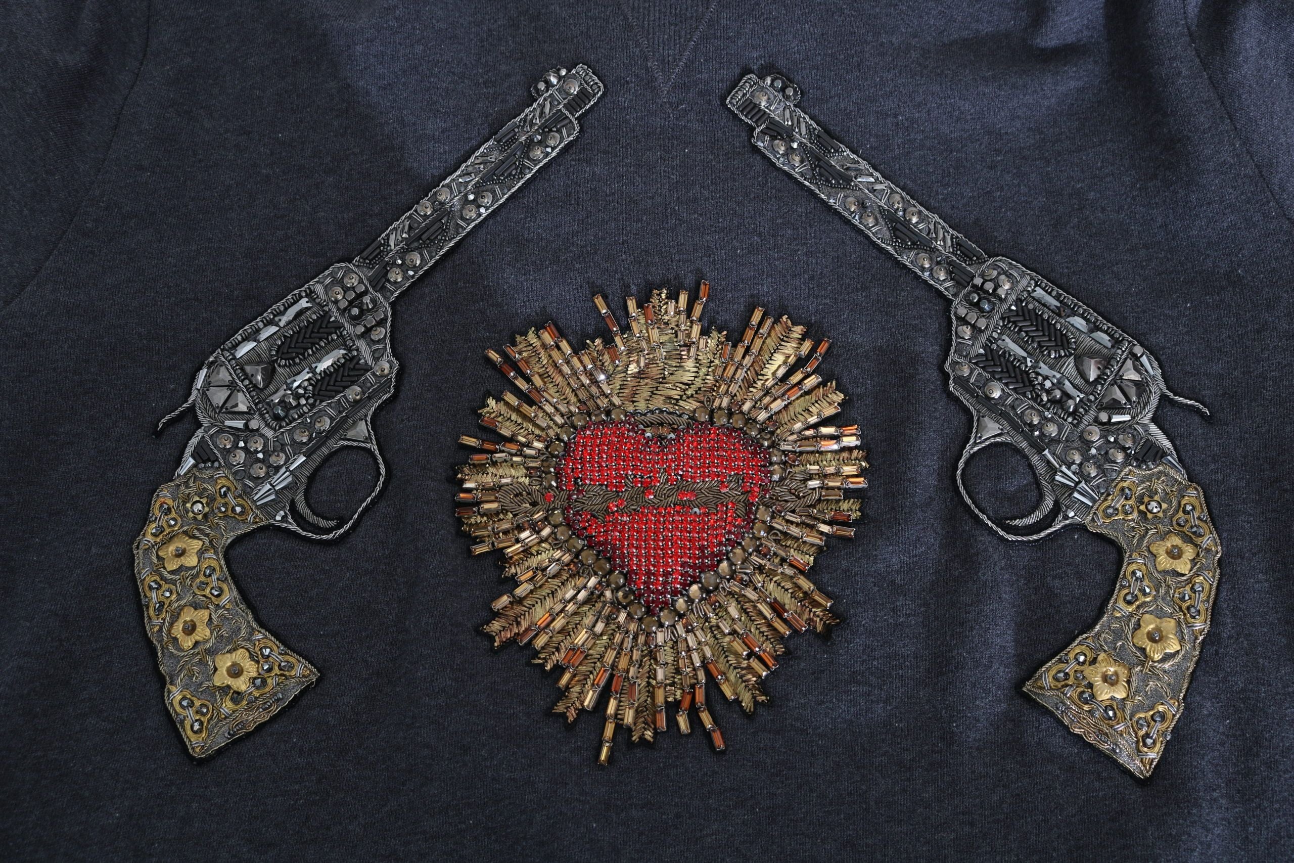Gray hooded sweater by Dolce & Gabbana featuring a red crystal heart and gun design, styled with a casual, modern look.