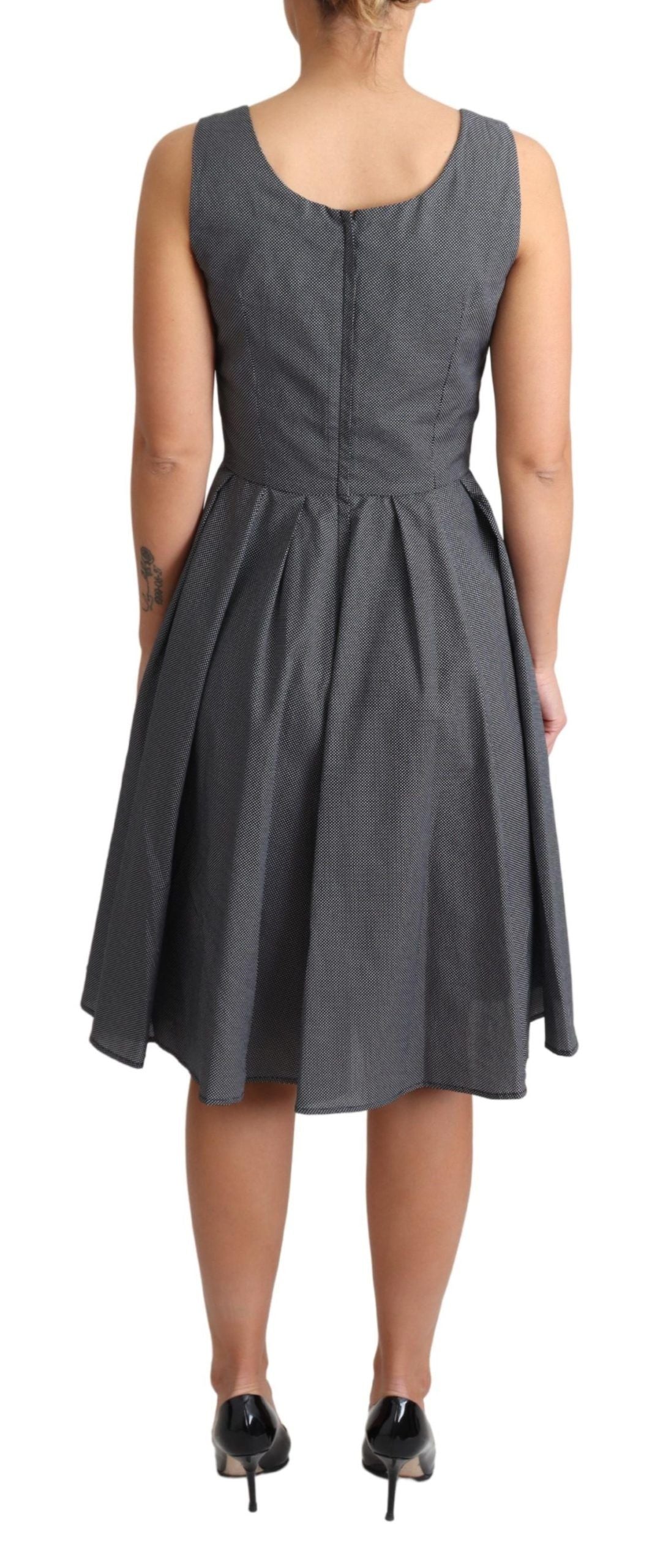 Black polka dotted cotton A-line dress by Dolce & Gabbana with a fitted waist and flared skirt, displayed on a hanger.