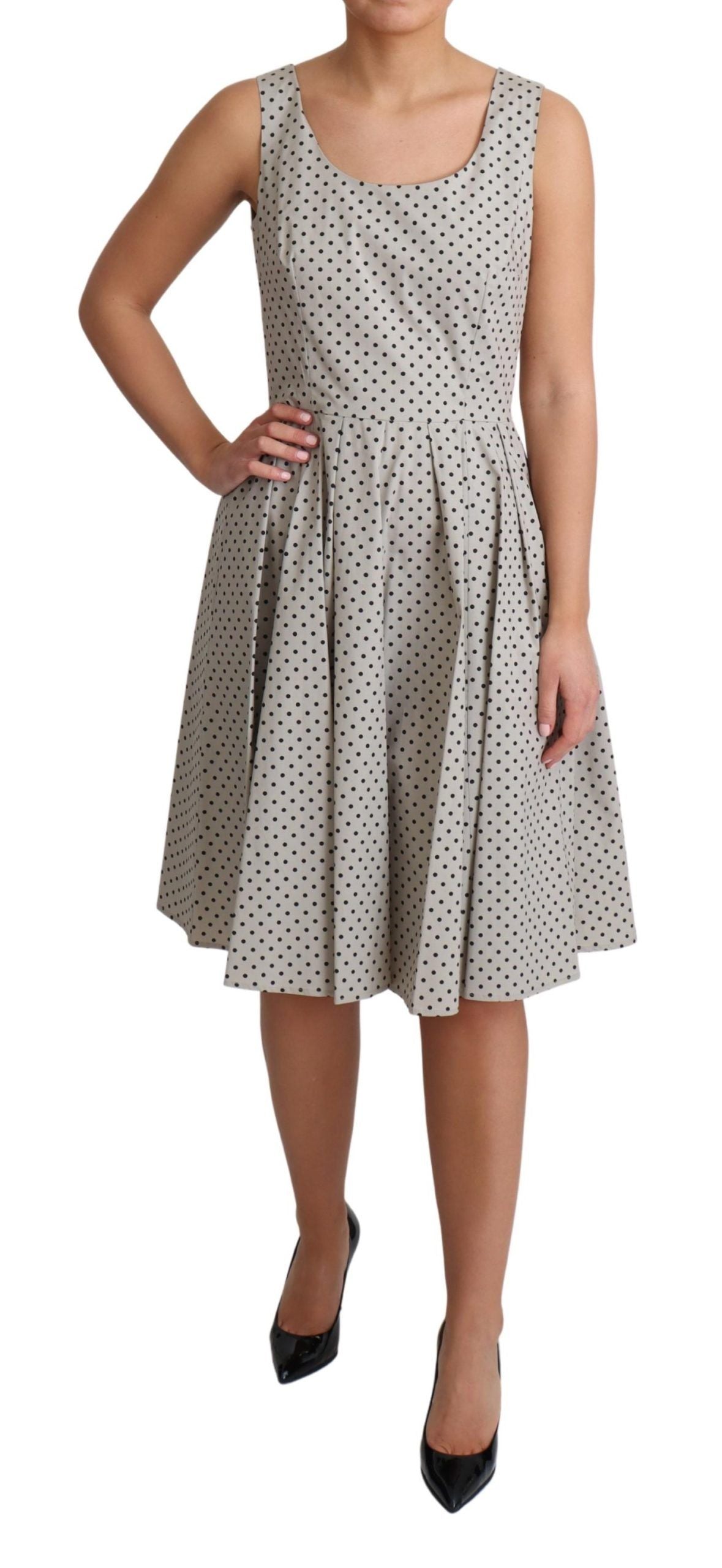 Beige polka dotted cotton A-line dress by Dolce & Gabbana hanging on a clothing rack with a subtle floral background.