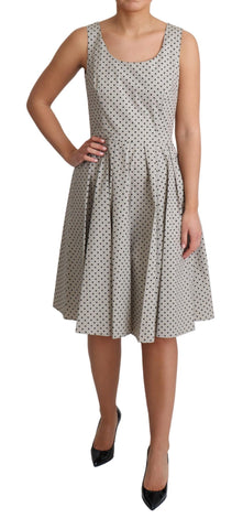 Beige polka dotted cotton A-line dress by Dolce & Gabbana hanging on a clothing rack with a subtle floral background.