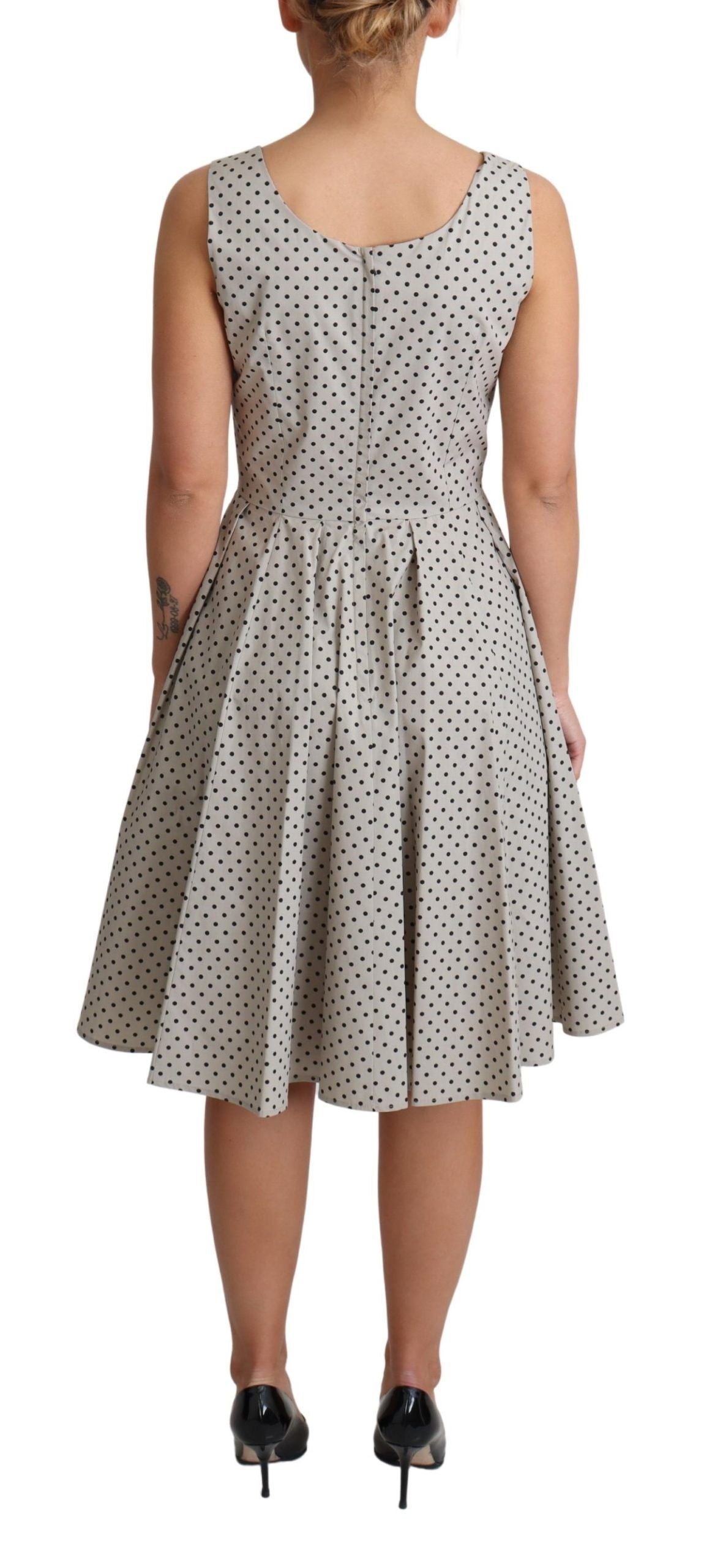 Beige polka dotted cotton A-line dress by Dolce & Gabbana, shown on a hanger with a flowy, classic silhouette.