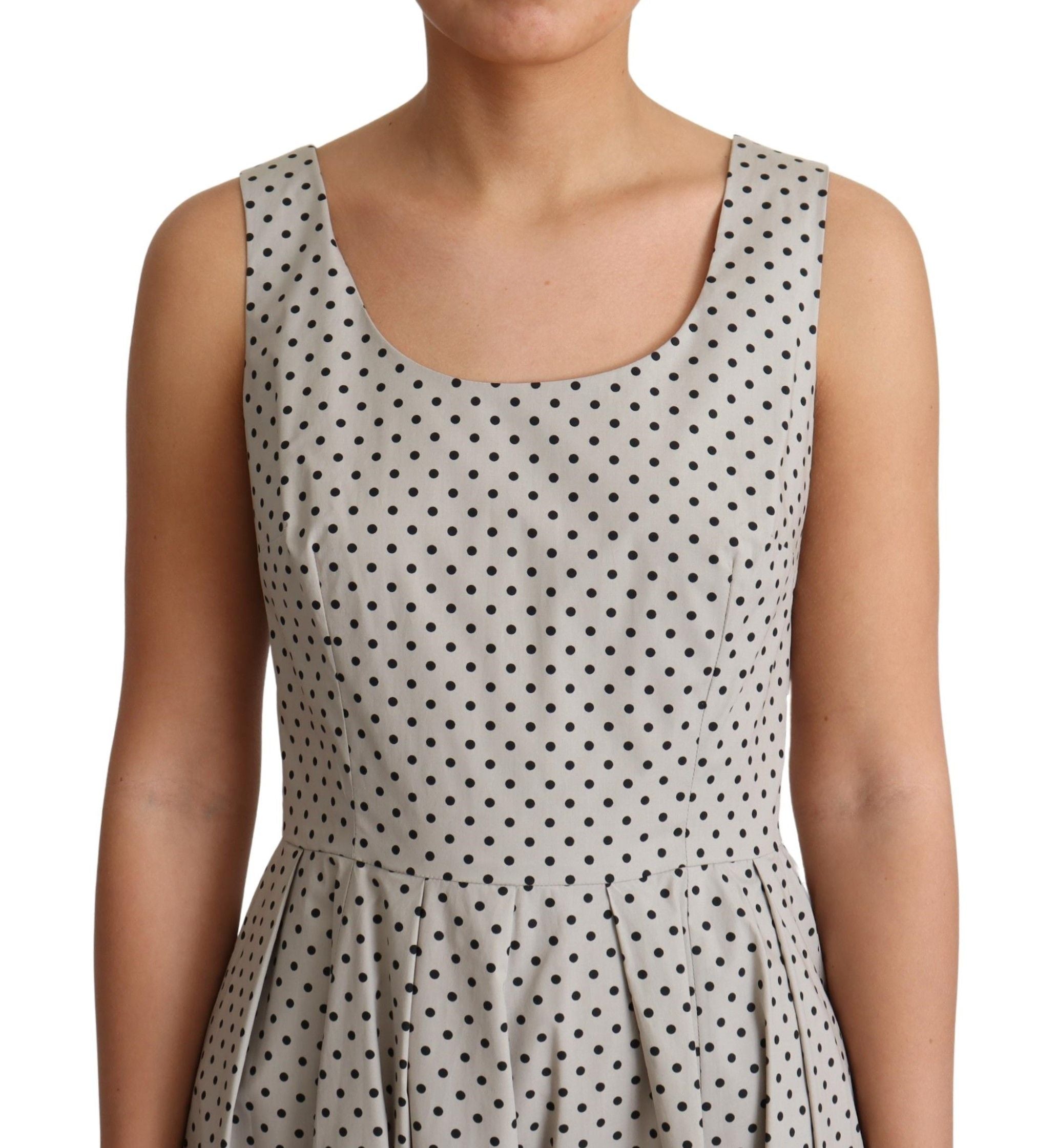 Beige polka dotted cotton A-line dress by Dolce & Gabbana displayed on a hanger against a white background.
