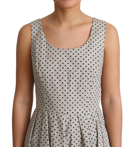 Beige polka dotted cotton A-line dress by Dolce & Gabbana displayed on a hanger against a white background.