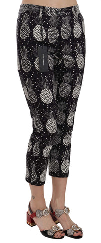 Black pineapple print skinny Capri pants by Dolce & Gabbana, featuring a vibrant tropical pattern and fitted silhouette.
