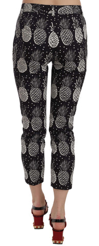 Black pineapple print skinny Capri pants by Dolce & Gabbana, featuring a fitted silhouette and tropical fruit pattern.