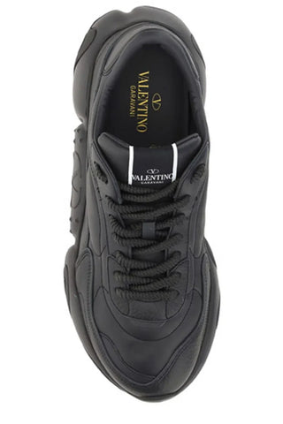 Black calf leather Valentino Garavani sneakers with sleek design and white rubber soles, displayed on a plain background.