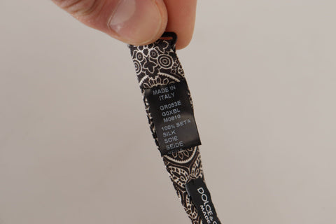 Black and white 100% silk adjustable neck papillon tie by Dolce & Gabbana, shown laid flat with smooth fabric and classic pattern.