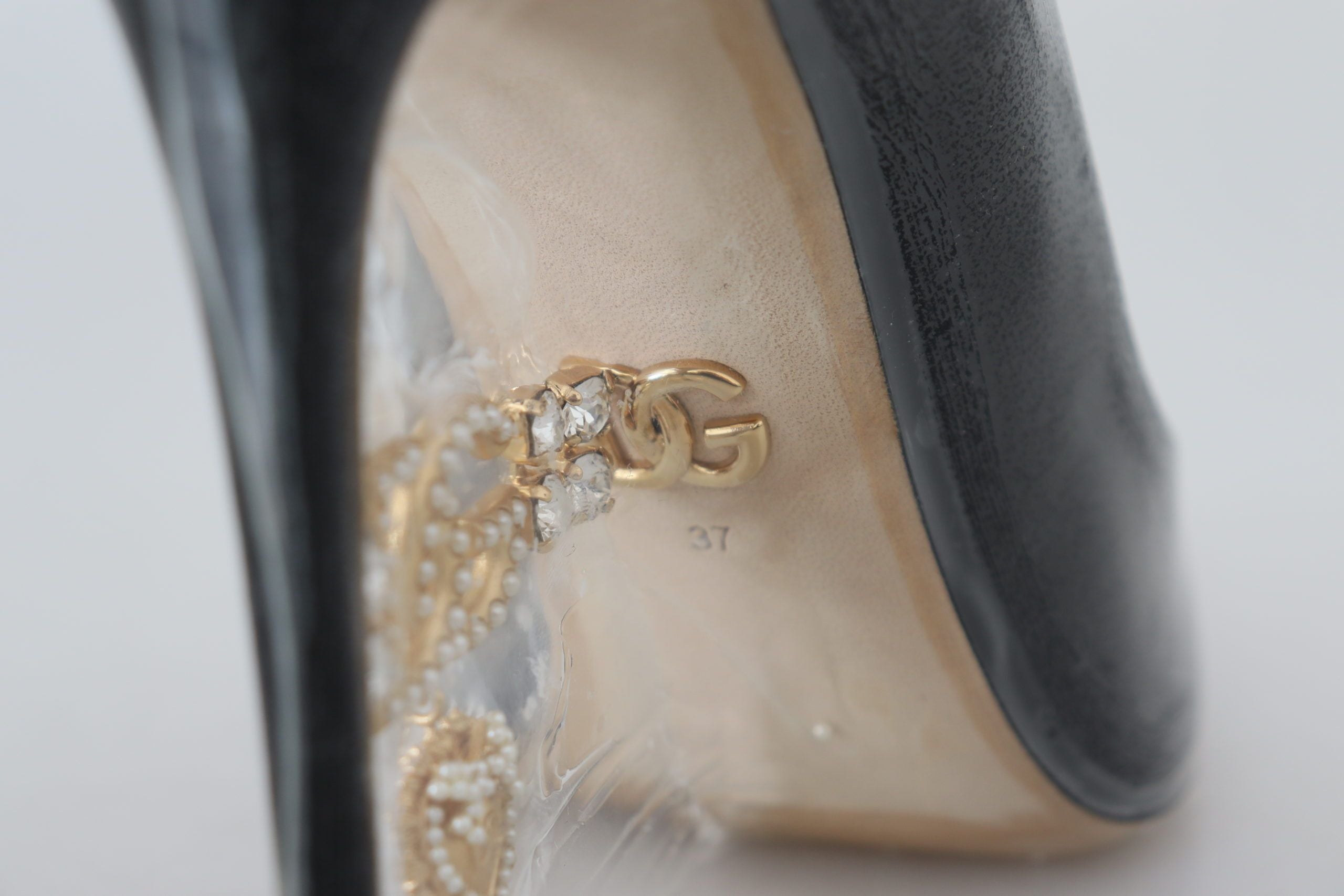 Dolce & Gabbana black leather heel pumps with plastic wrapping, stylish women's footwear for formal or evening wear.