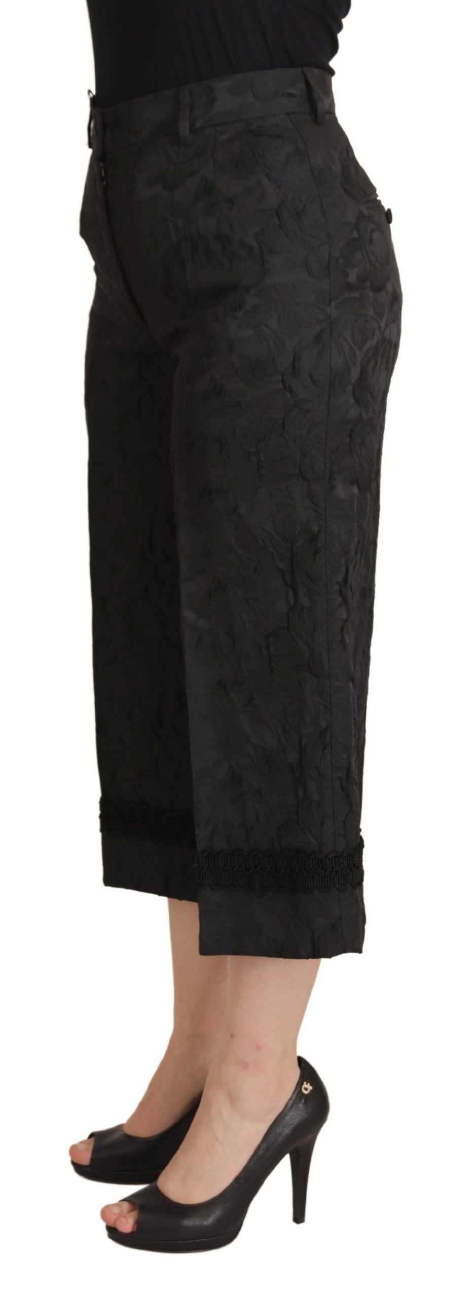Dark black brocade high waist cropped pants by Dolce & Gabbana, featuring intricate fabric pattern and tailored fit.