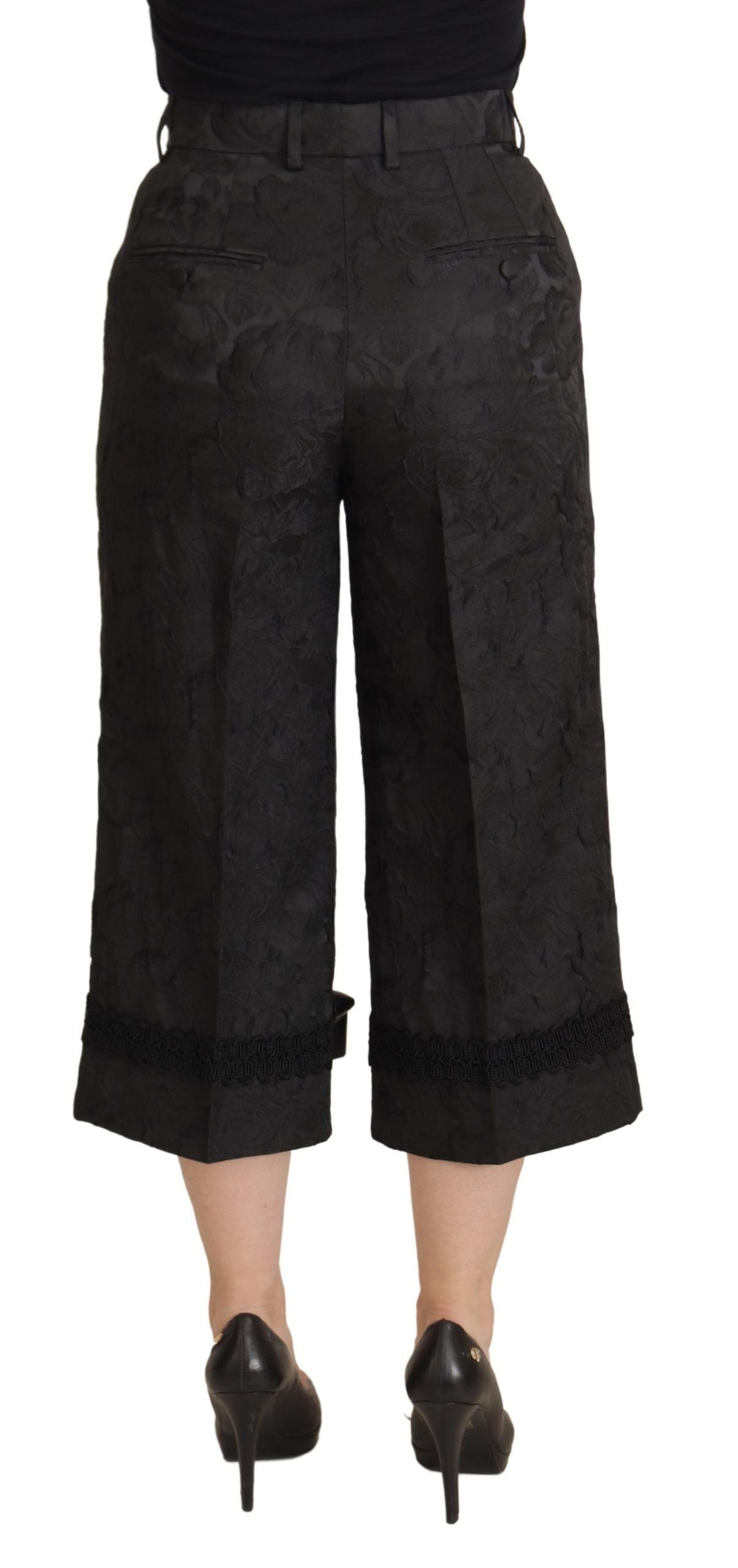 Black brocade cropped high-waist pants by Dolce & Gabbana, featuring intricate fabric details and a tailored fit.