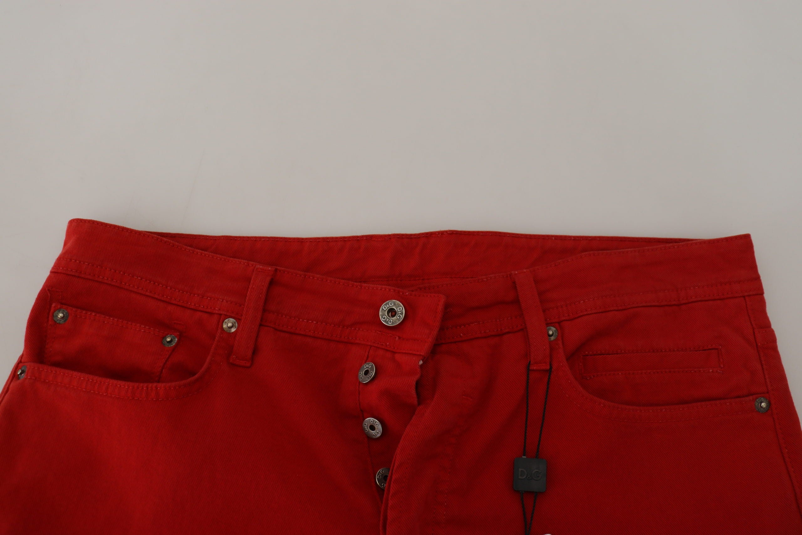 Red cotton straight fit men's denim jeans by Dolce & Gabbana, shown on a hanger with front pockets and classic stitching.