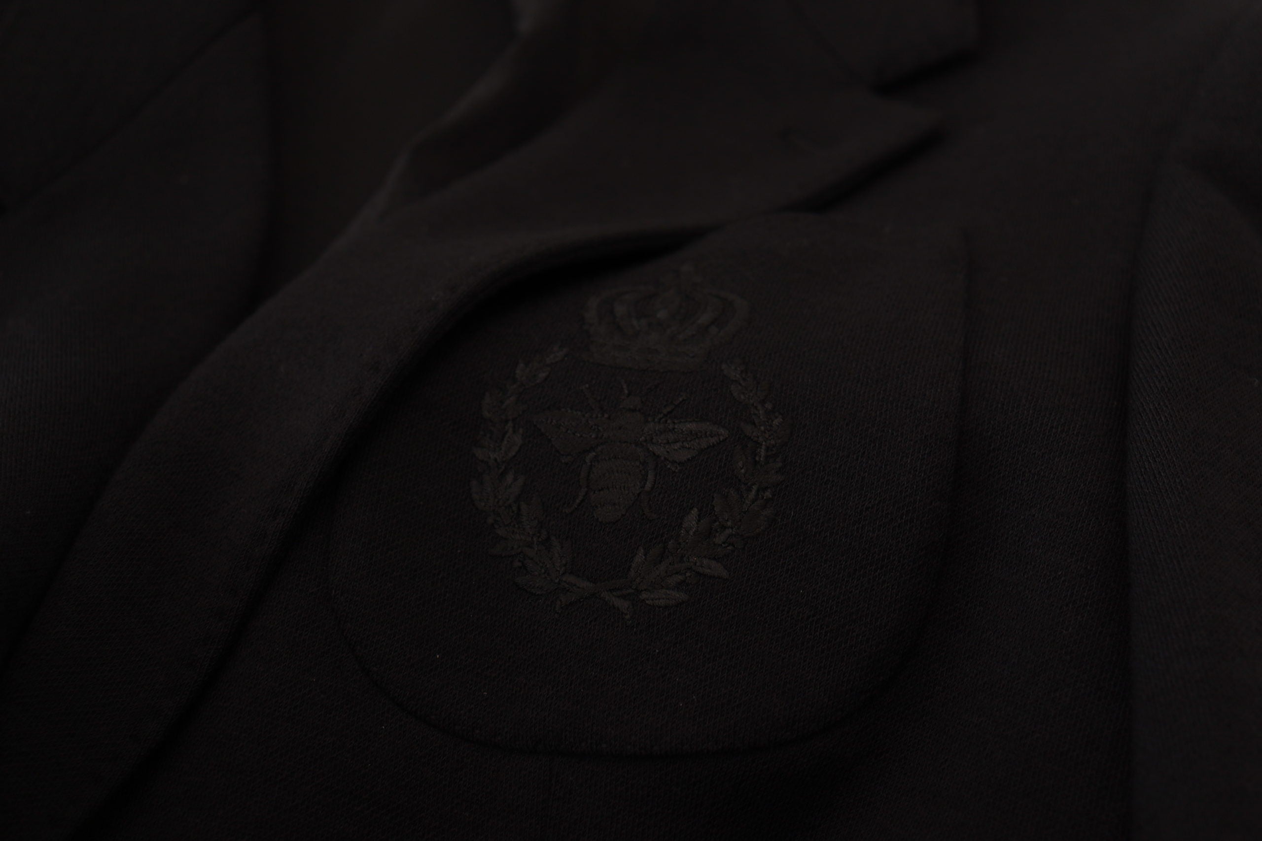 Black wool blazer jacket with a slim fit and crown design by Dolce & Gabbana, shown hanging on a wooden hanger.