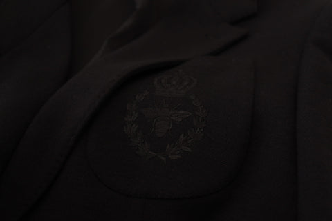 Black wool blazer jacket with a slim fit and crown design by Dolce & Gabbana, shown hanging on a wooden hanger.