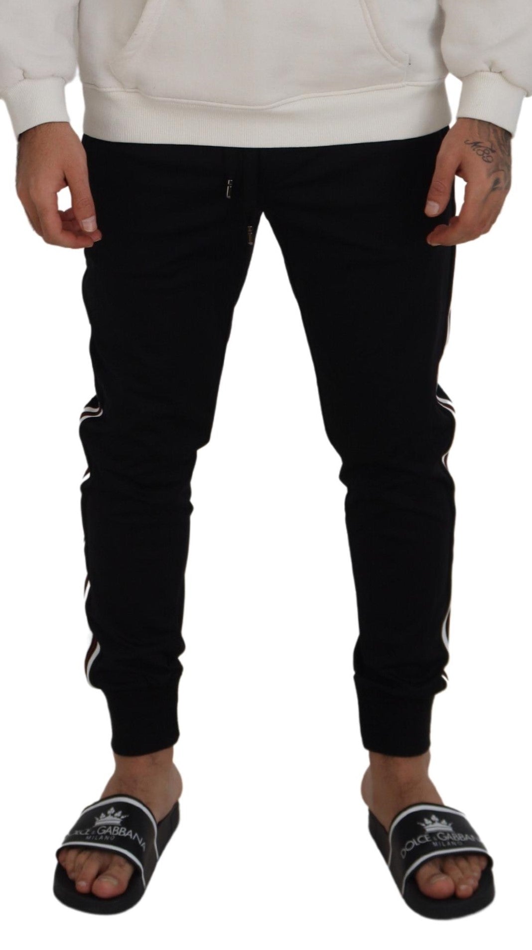 Black Dolce & Gabbana men's jogger pants with DG print, featuring a relaxed fit and elastic waistband, shown on a hanger.