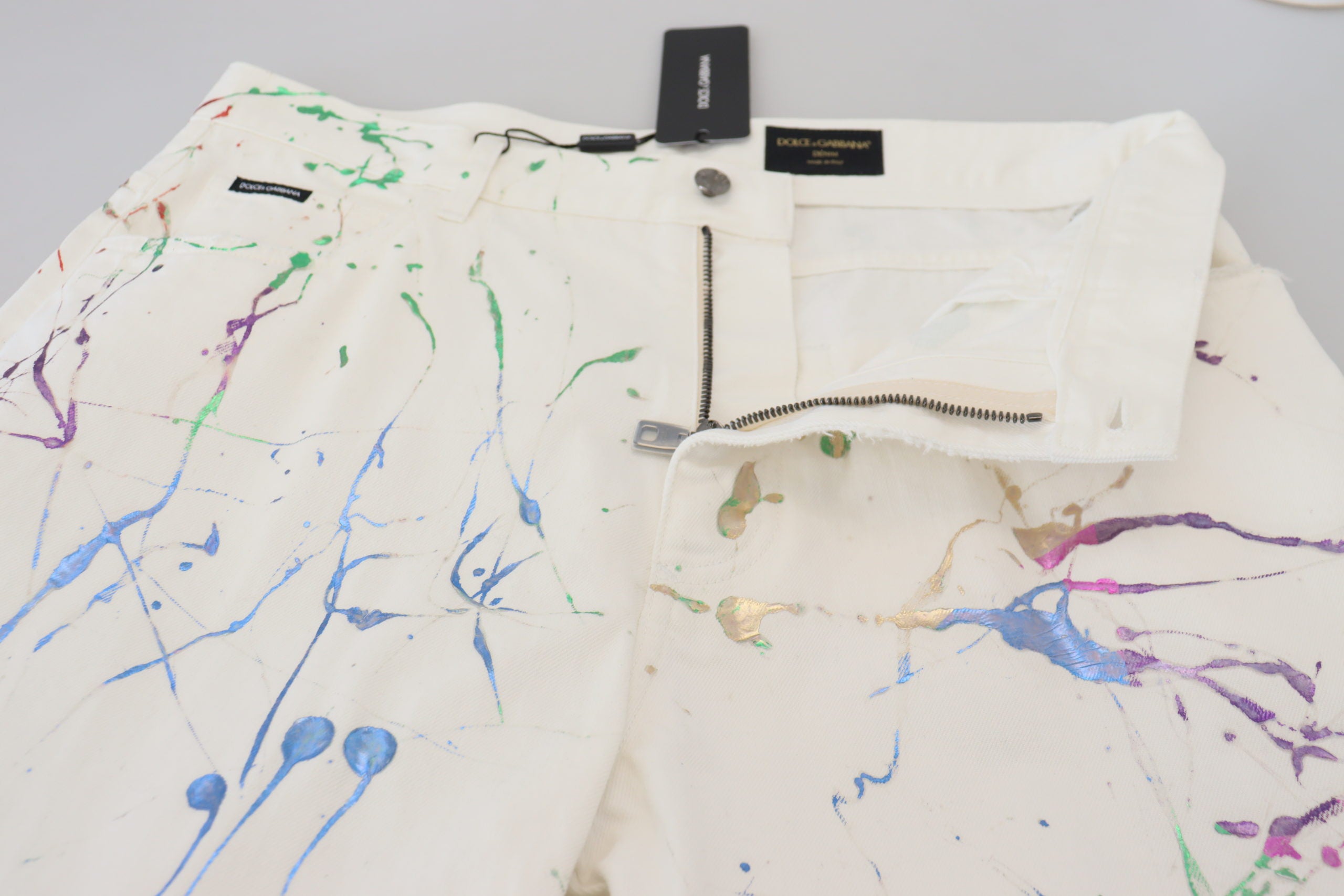 White cotton denim pants with colorful splash print by Dolce & Gabbana, featuring a relaxed fit and stylish design.