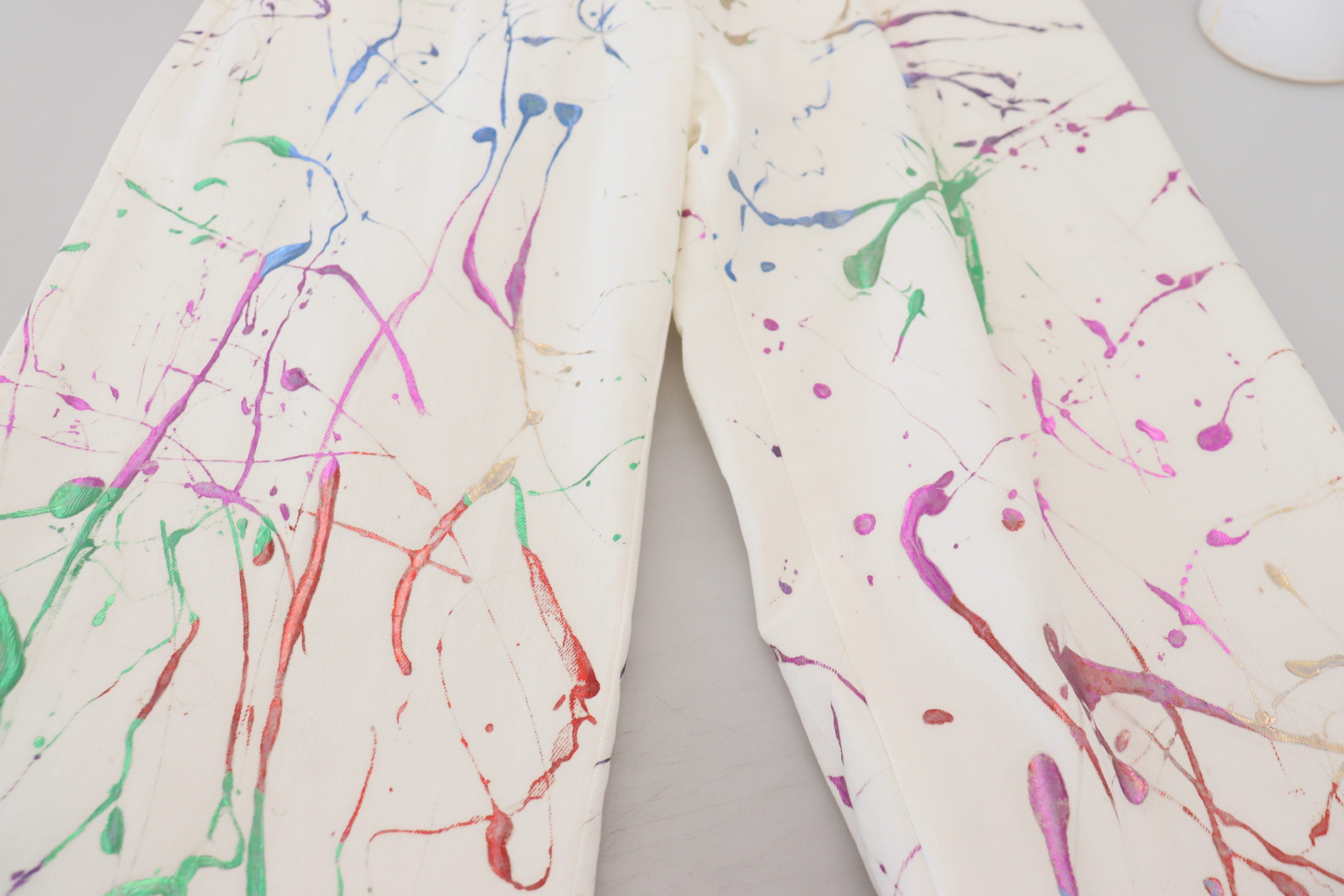 White cotton denim pants with colorful splash print by Dolce & Gabbana, featuring a relaxed fit and casual style.