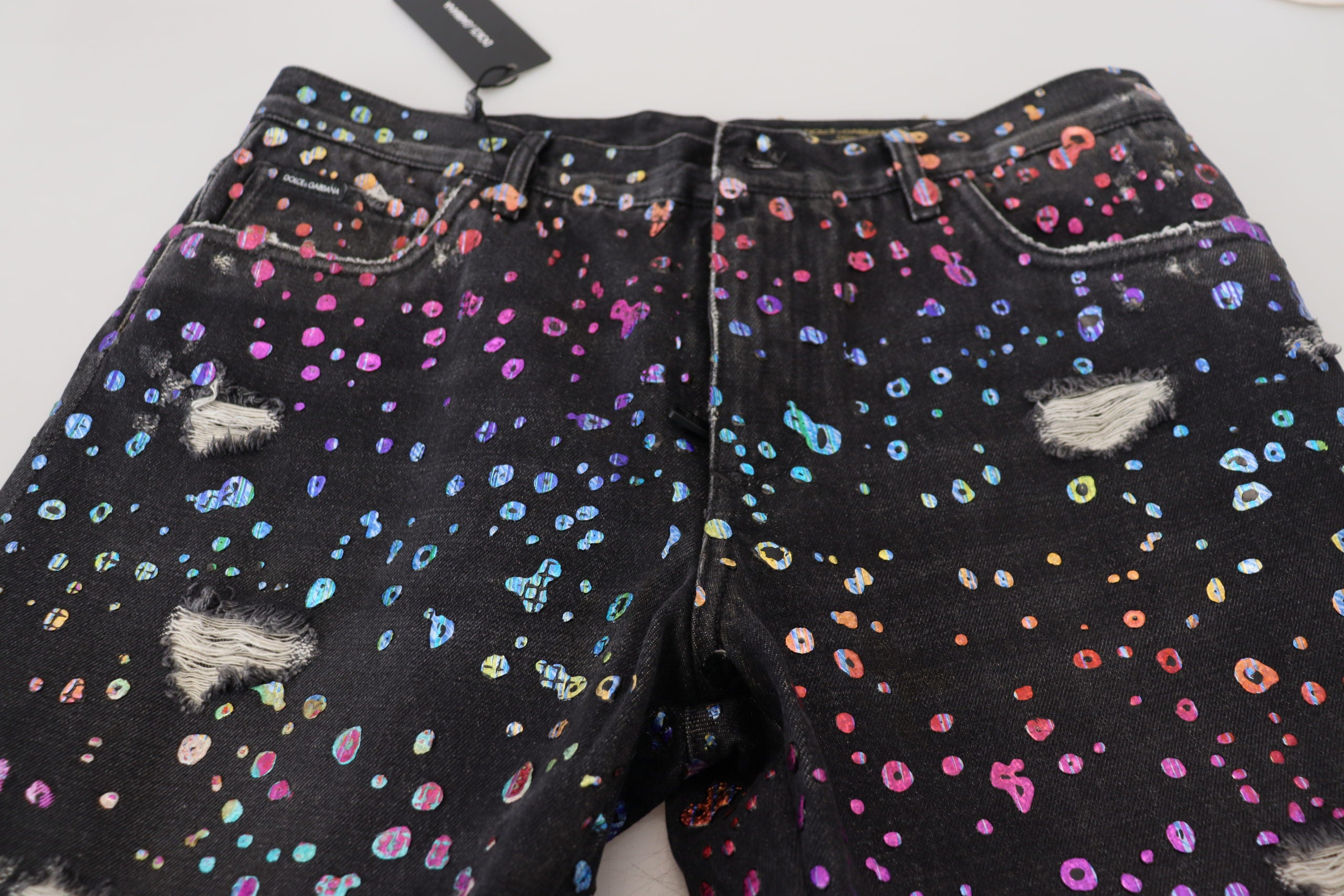 Black multicolor print tattered denim jeans by Dolce & Gabbana with distressed details and vibrant patchwork design.