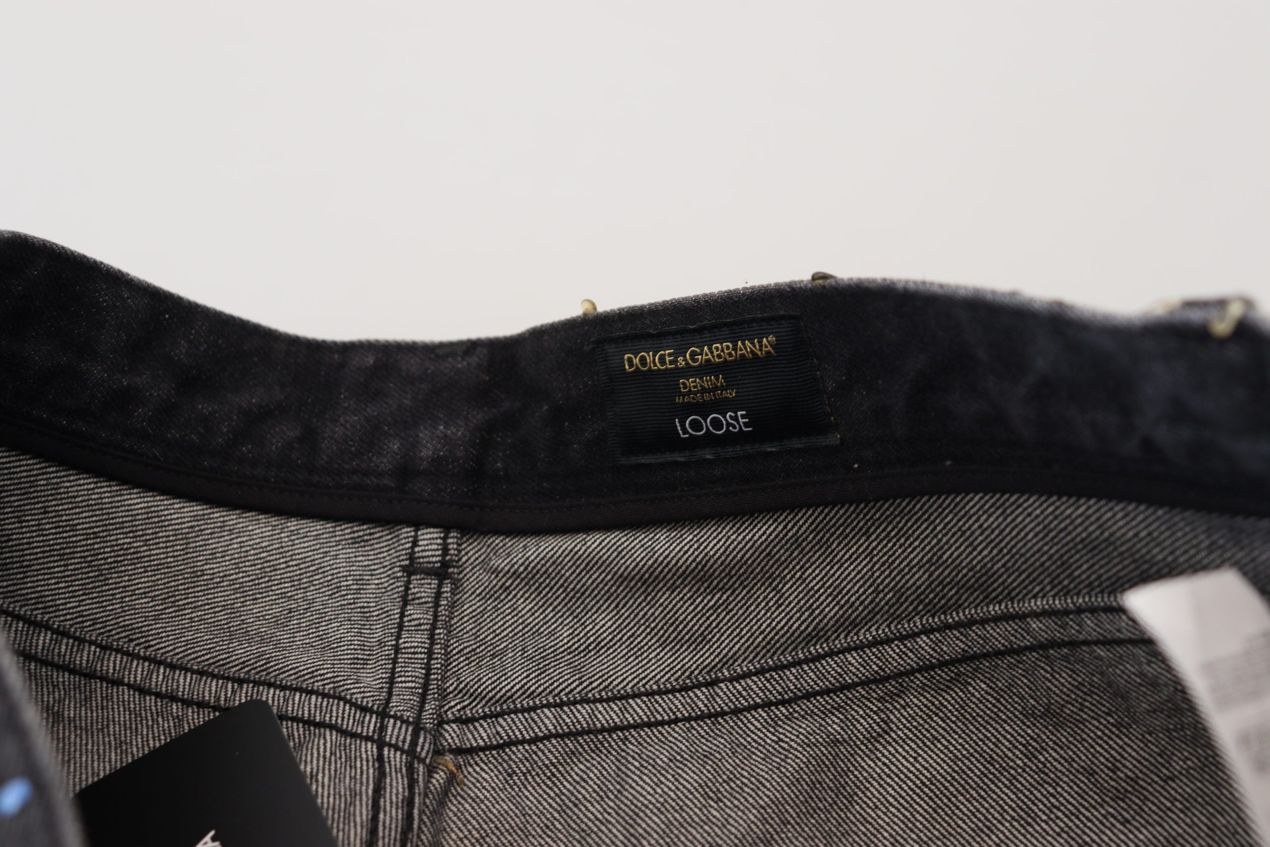 Black multicolor print tattered denim jeans by Dolce & Gabbana, featuring distressed details and vibrant floral patterns.