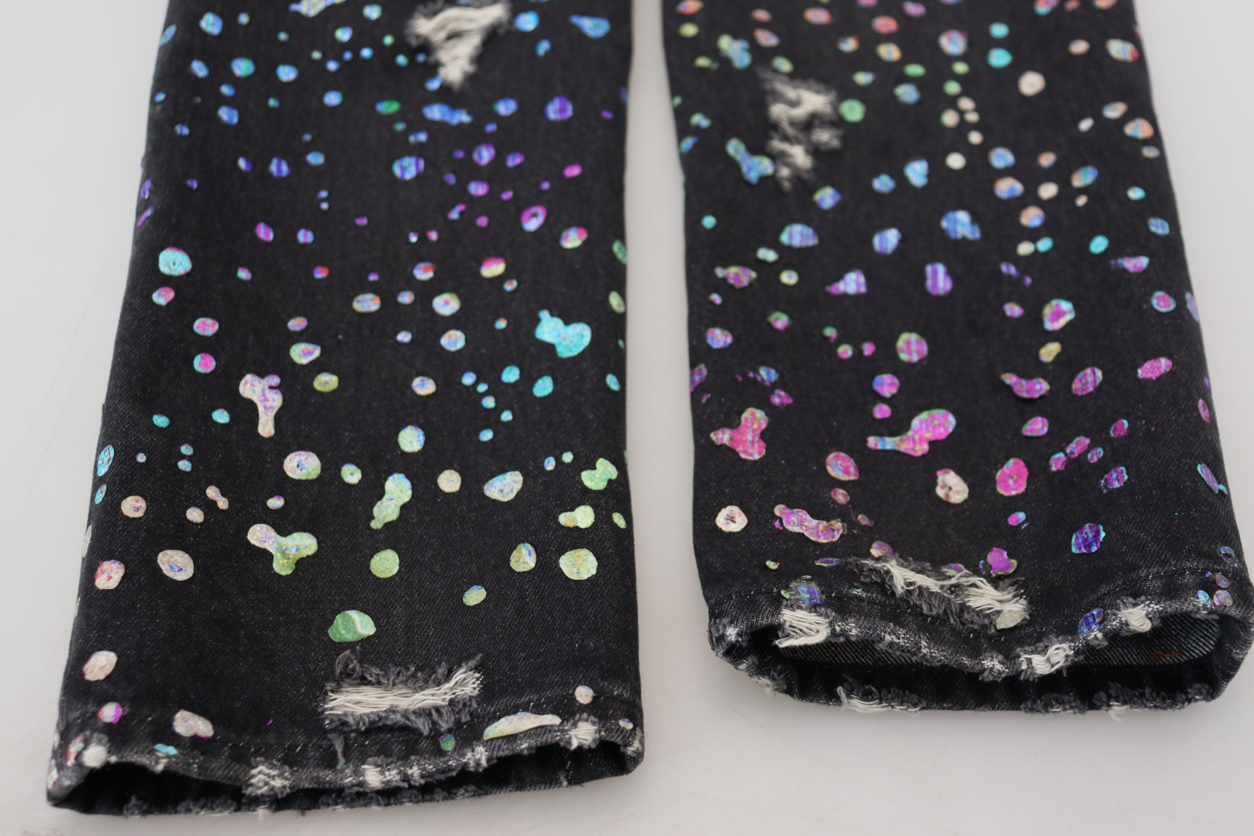 Black multicolor print tattered denim jeans by Dolce & Gabbana with distressed details and vibrant pattern accents.