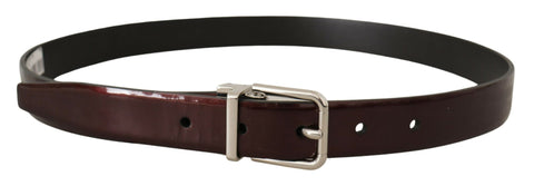 Brown patent leather belt with silver metal buckle from Dolce & Gabbana, shown with close-up of textured leather and sleek buckle detail.
