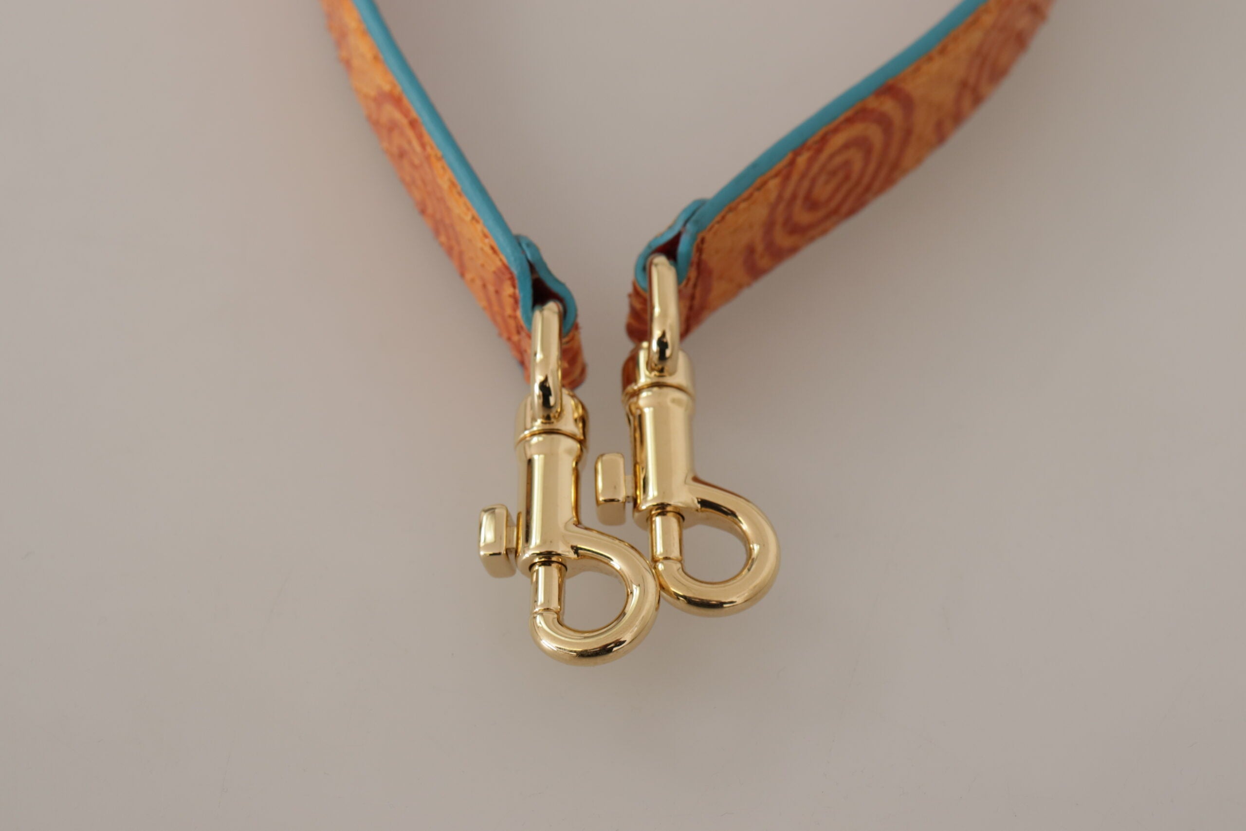 Orange leather shoulder strap with swirl print for Dolce & Gabbana bags, featuring adjustable design and gold-tone hardware.