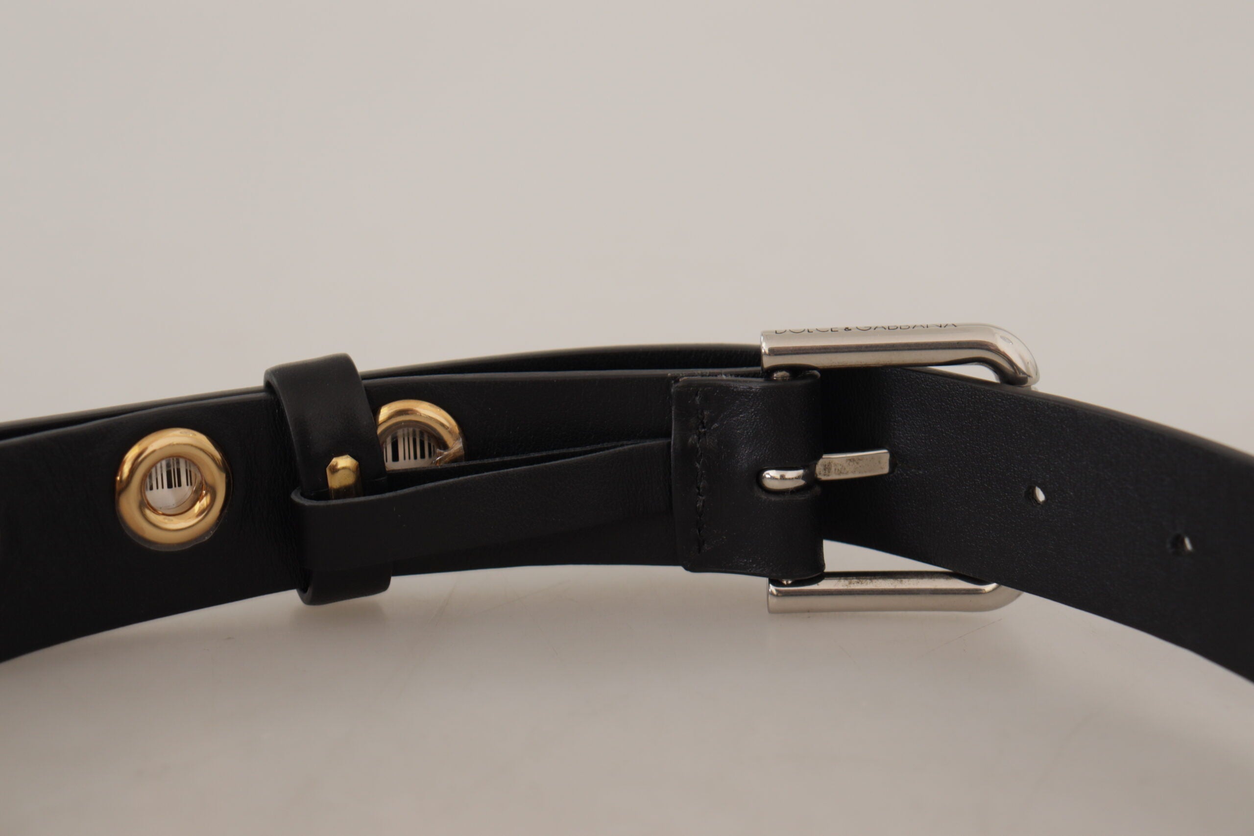 Black leather belt with silver eyelet accents and metal buckle by Dolce & Gabbana, shown on a neutral background.
