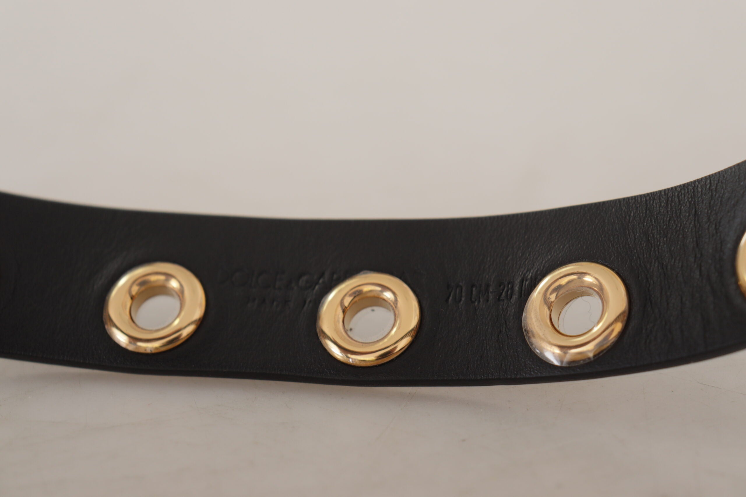 Black leather belt with silver eyelet metal buckle by Dolce & Gabbana, showing close-up of the buckle and textured leather strap.