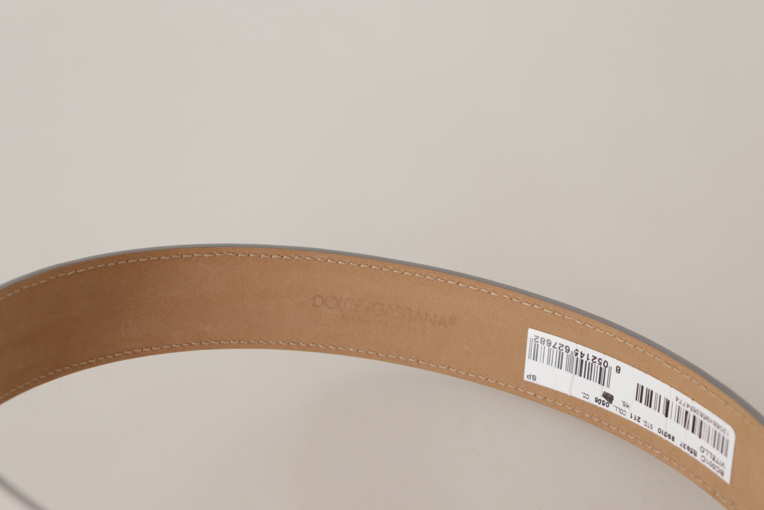 Silver leather belt with gold tone logo metal buckle by Dolce & Gabbana, shown with close-up of buckle detail.