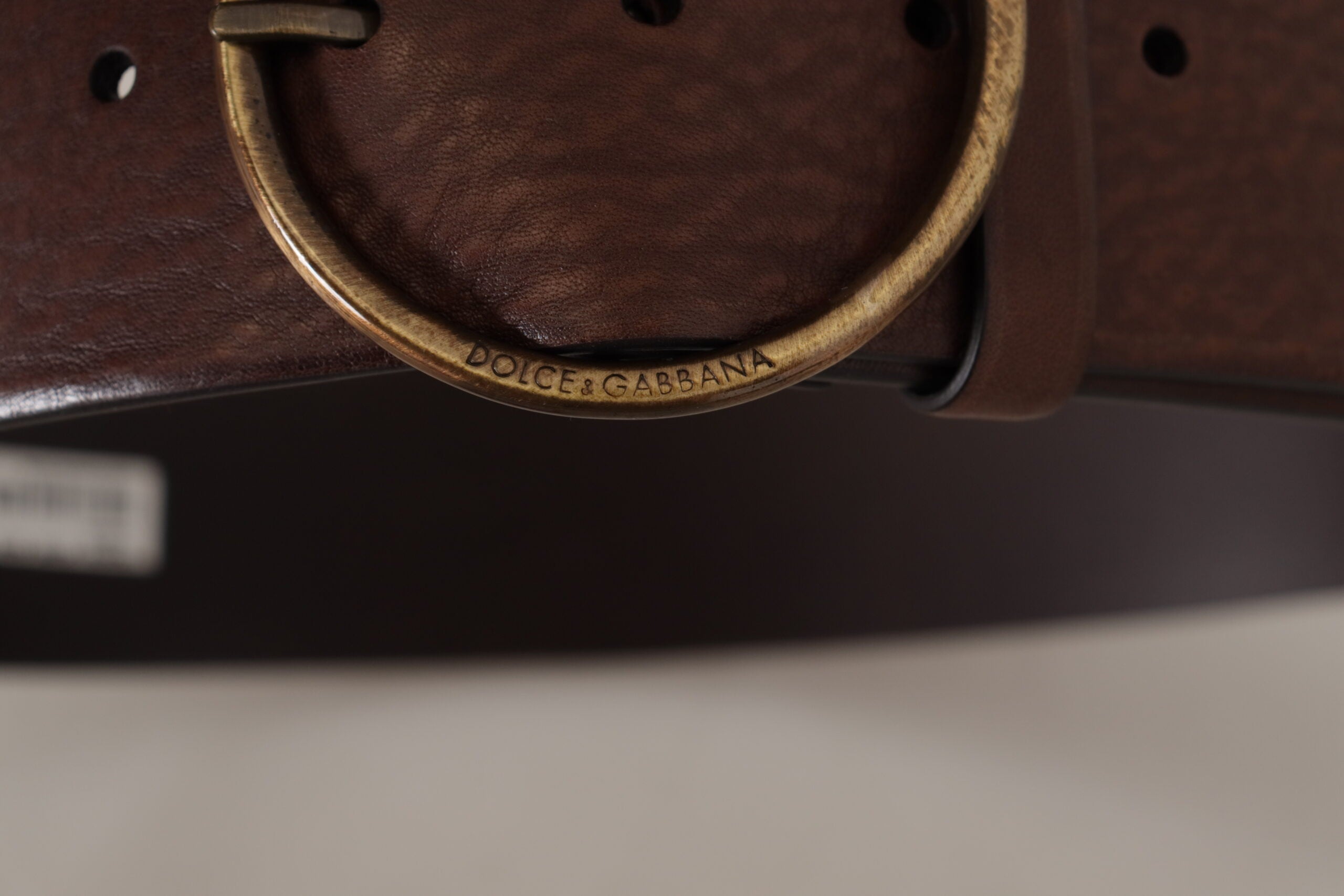 Brown leather wide waist belt with a metal round logo buckle from Dolce & Gabbana, displayed on a plain background.