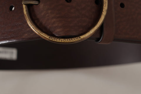 Brown leather wide waist belt with a metal round logo buckle from Dolce & Gabbana, displayed on a plain background.