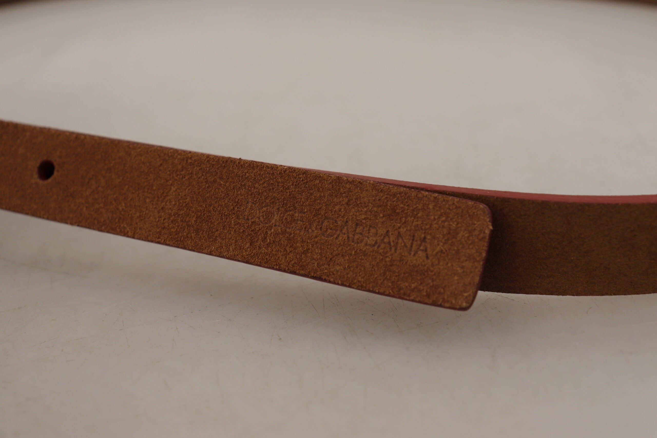 Brown leather belt with engraved metal waist buckle featuring Dolce & Gabbana logo, stylish accessory for men.