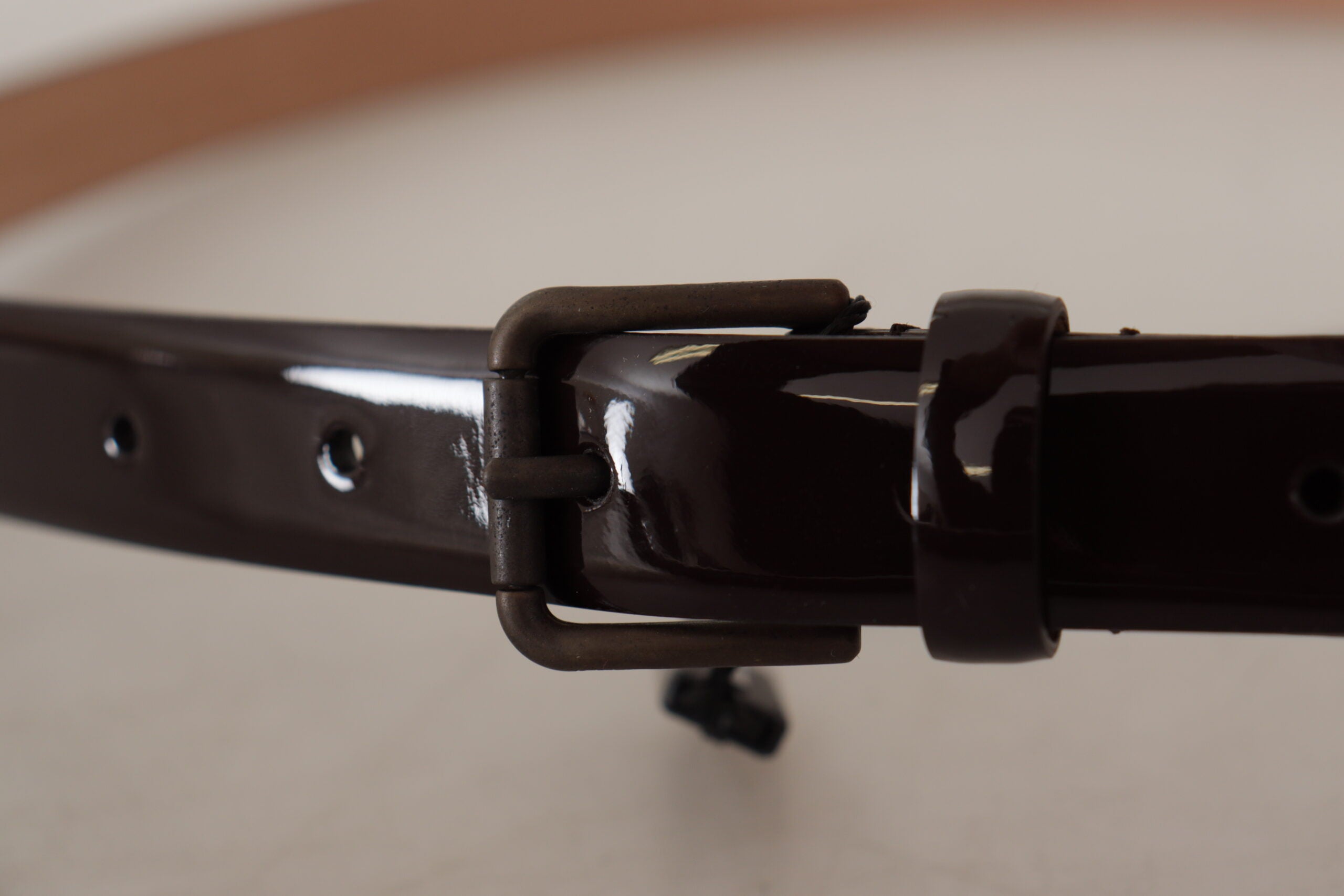 Black patent leather Dolce & Gabbana waist belt with metal logo buckle, featuring a sleek and stylish design.