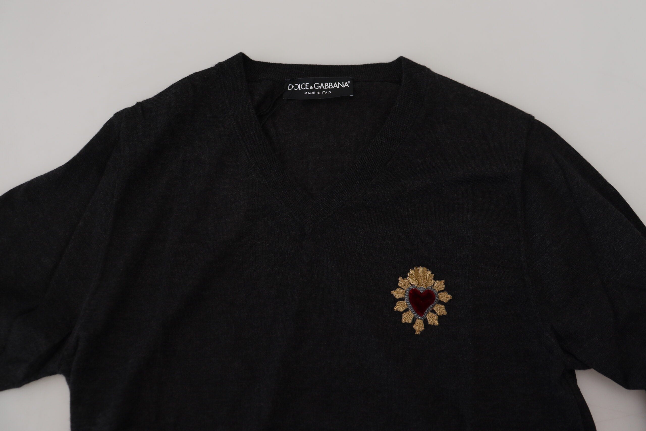 Gray cashmere V-neck sweater with gold heart detail by Dolce & Gabbana, shown on a model.