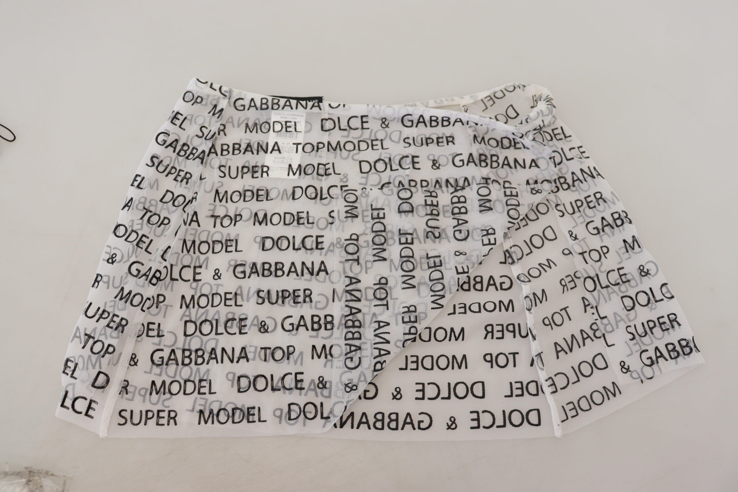 White see-through A-line mini skirt with logo detailing by Dolce & Gabbana, styled with a sleek, modern silhouette.