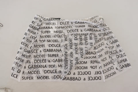 White see-through A-line mini skirt with logo detailing by Dolce & Gabbana, styled with a sleek, modern silhouette.