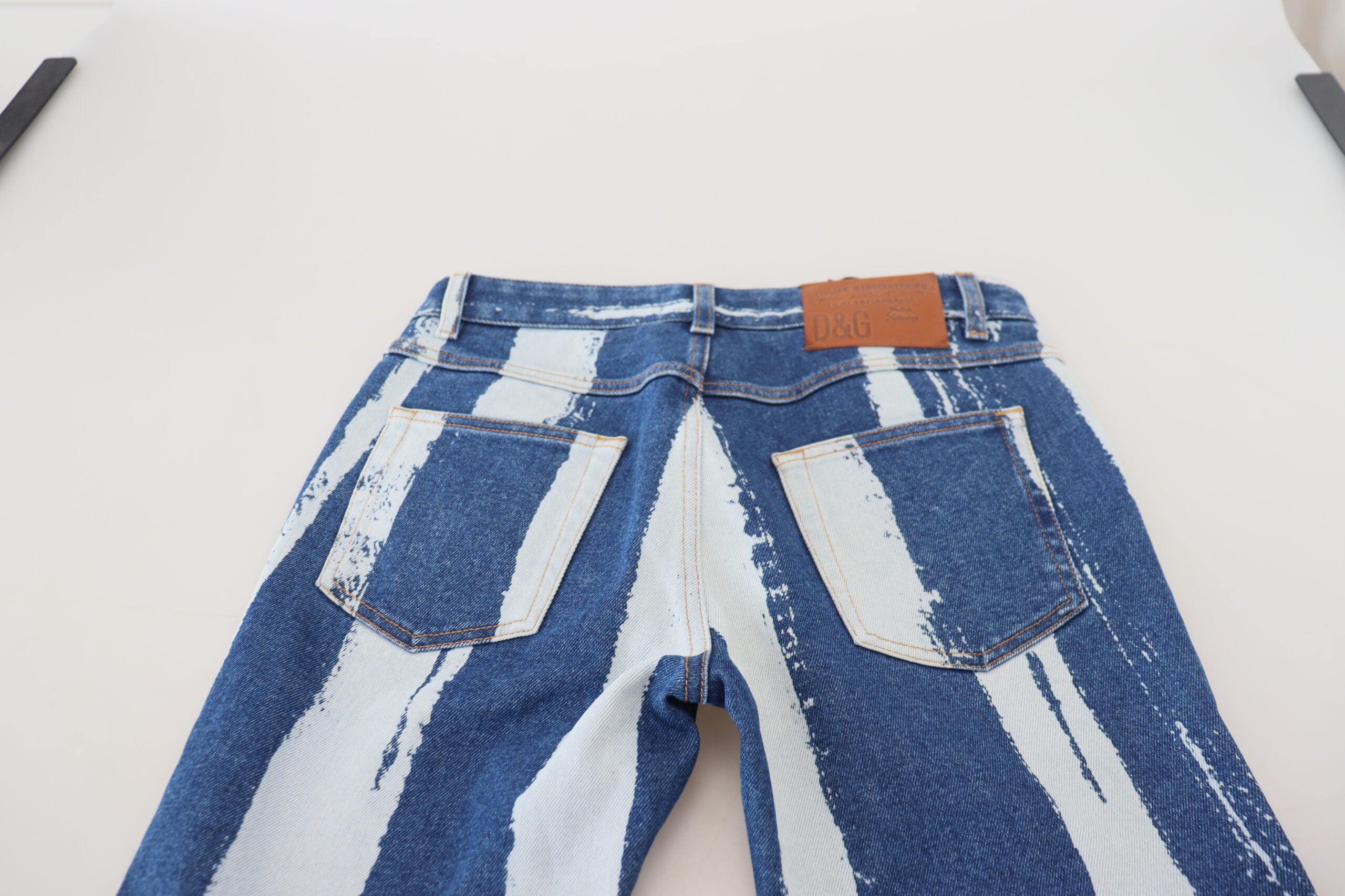 Cobalt blue Dolce & Gabbana skinny denim jeans with white stripe patterns, made of cotton, close-up view of the product.