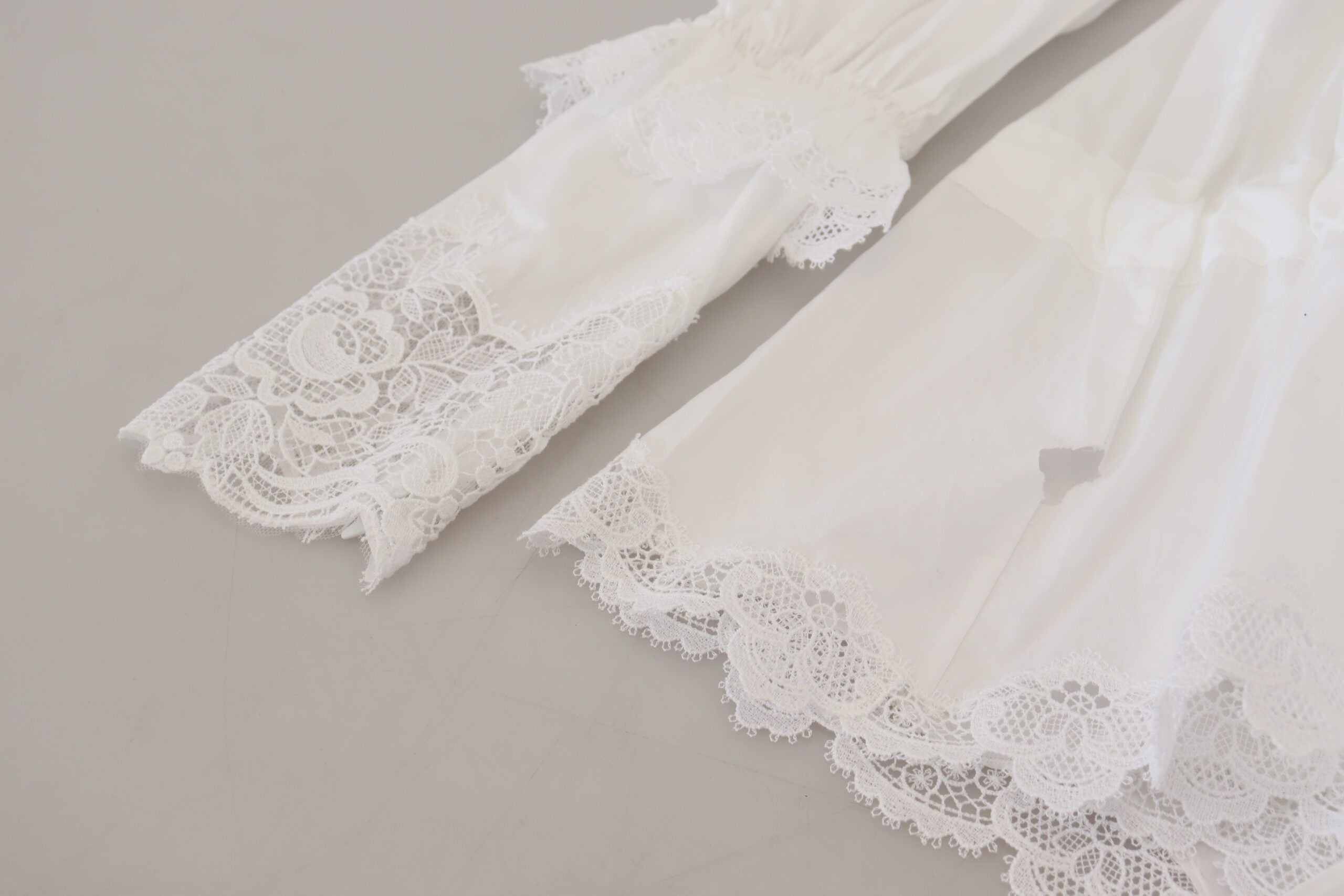 White cotton blouse with lace trim and turtle neck, designed by Dolce & Gabbana, shown on a model.