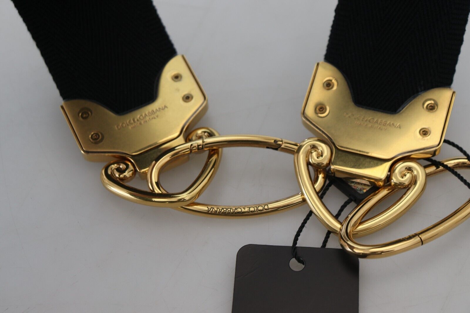 Dolce & Gabbana black brass bag shoulder strap with gold logo print, featuring adjustable hardware for stylish carrying.