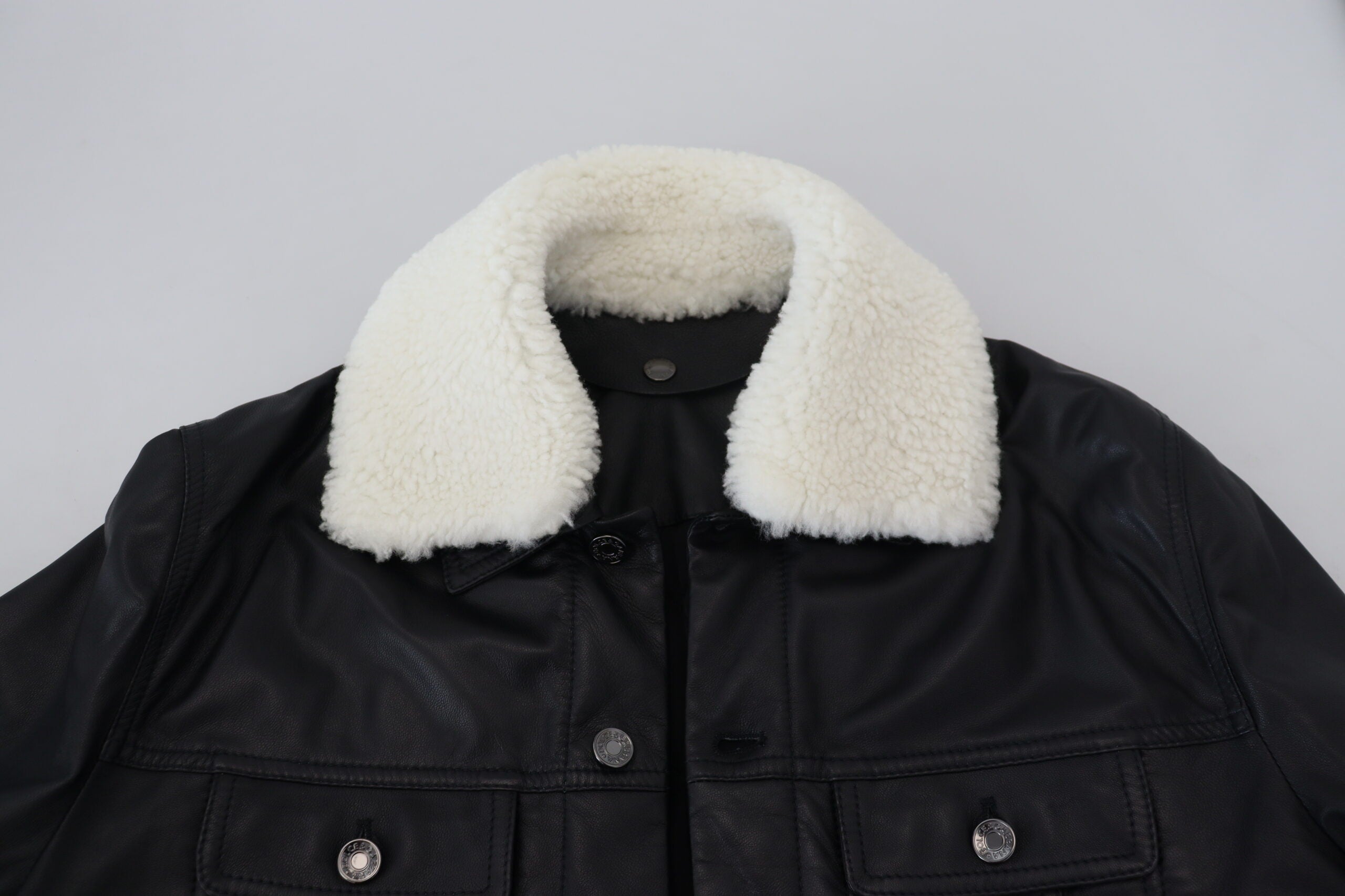 Black lamb leather men's coat with a collar, designed by Dolce & Gabbana, shown on a hanger against a neutral background.