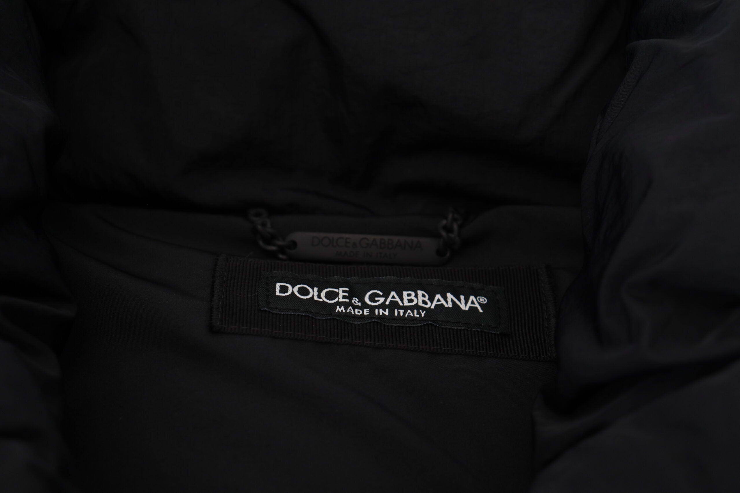 Black sleeveless Dolce & Gabbana jacket with metal embellishments, featuring a stylish sleeveless design and luxe detailing.
