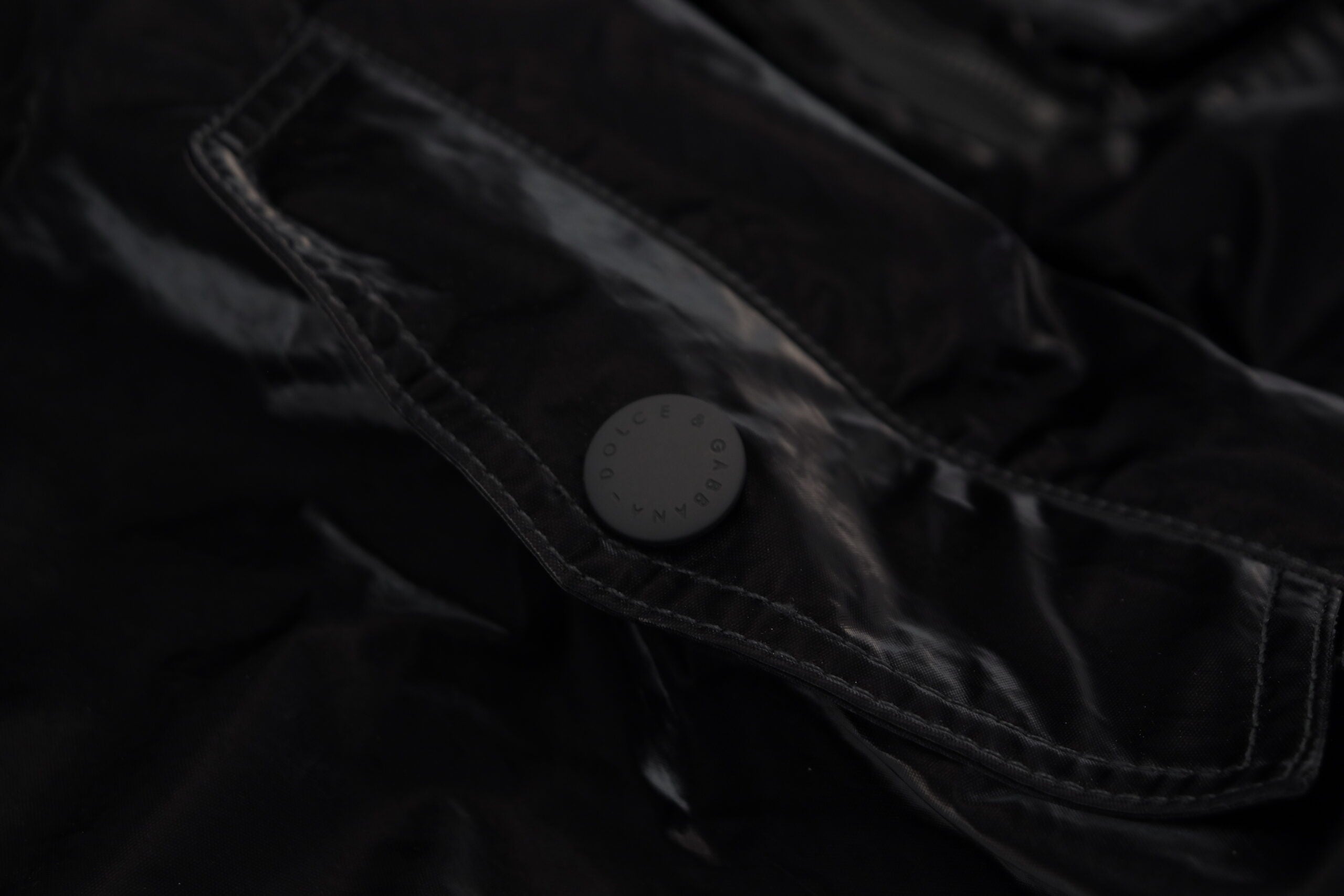 Black nylon hooded full-zip bomber jacket by Dolce & Gabbana, shown with front view and adjustable hood.