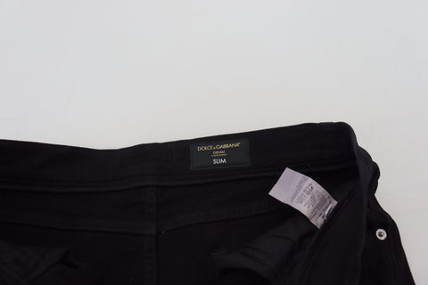 Black slim fit tattered denim cotton jeans by Dolce & Gabbana, shown with distressed details and classic five-pocket design.