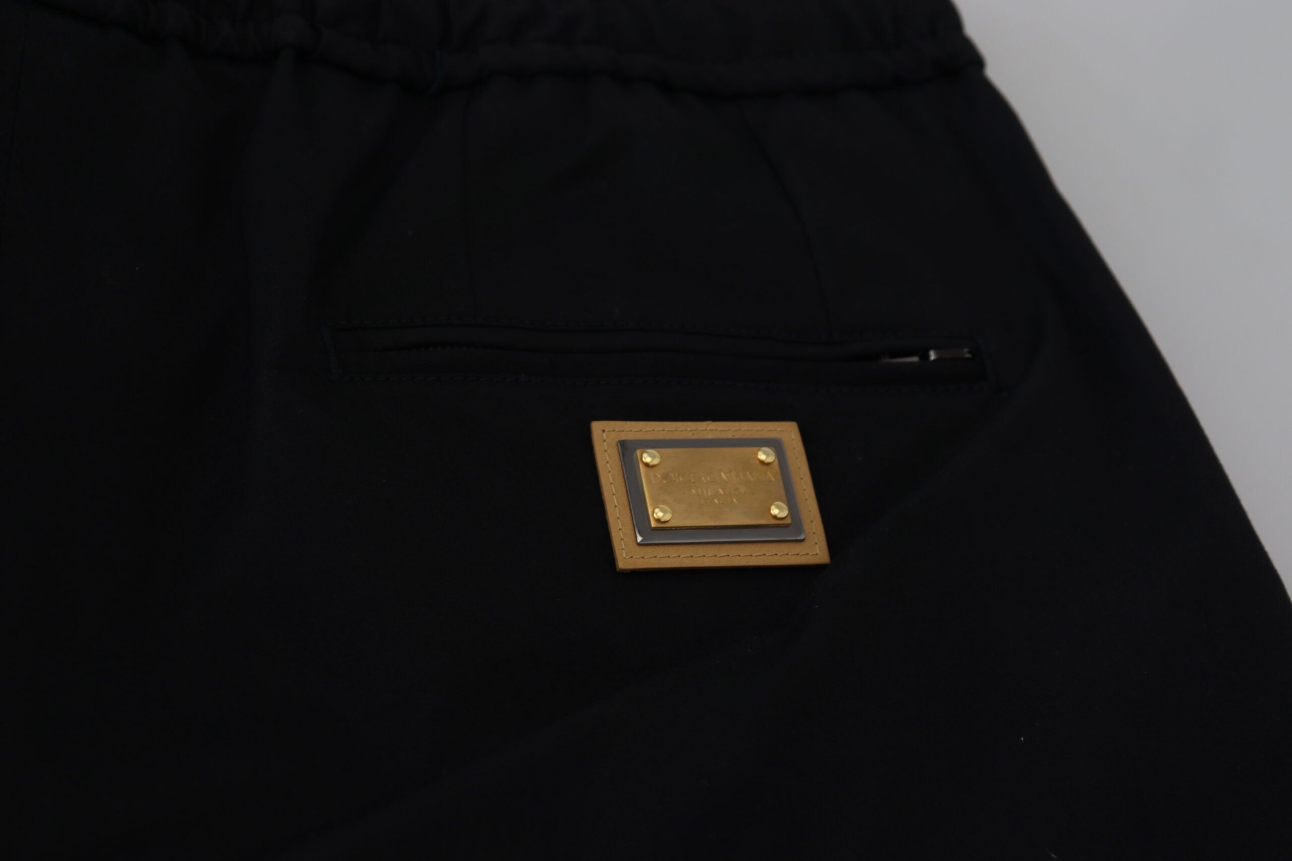 Black cotton cropped pants with elastic waist and DG logo from Dolce & Gabbana, showing a close-up of the fabric and design details.